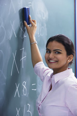 teacher smiling as she erases at chalkboard