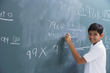 boy at chalkboard, smiling at camera