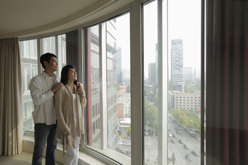 Young couple looking out large windows at view
