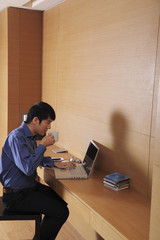 Young man working on laptop computer drinking coffee