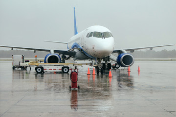 The plane at the airport on loading. Plane at the airport. Rain at the airport. Plane in the rain. Airport. Airplane parking at the airport.