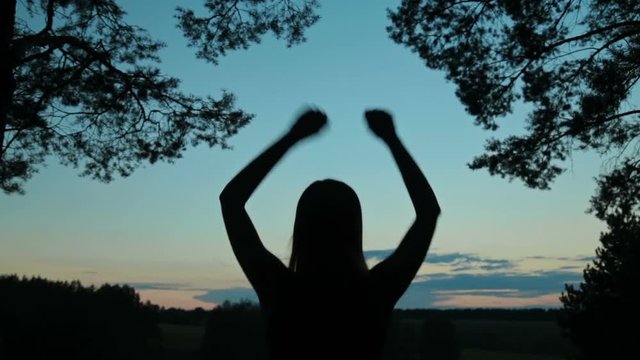 Young woman jumping and dancing in the forest after sunset. Freedom and happiness concept.