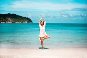 Young woman practicing yoga on the beach