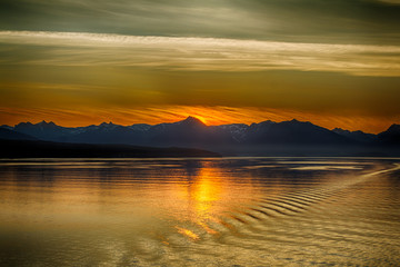 Sun setting behind Alaskan Mountain reflecting in the ocean