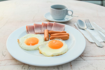 Breakfast with Fried egg, Ham, Sausage and black coffee on marble table.