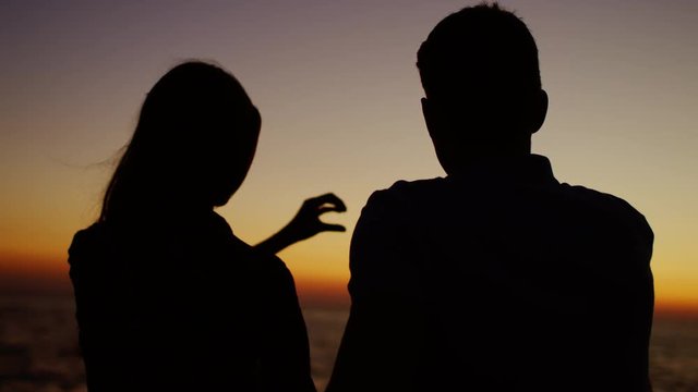 Romantic couple making a symbol of love at the sea shore