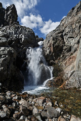Fototapeta na wymiar Waterfall on mountain river and blue sky with clouds