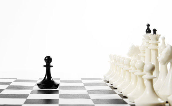 Lonely black pawn in front of enemy team. Courage and boldness. Concept with chess pieces against white background