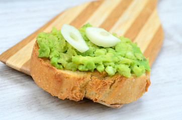 bruschetta of avocado on wooden spoon