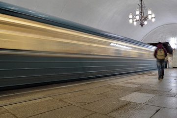 Fototapeta na wymiar Поезд метро, въезжающий на станцию, и размытый силуэт пассажира у конца платформы