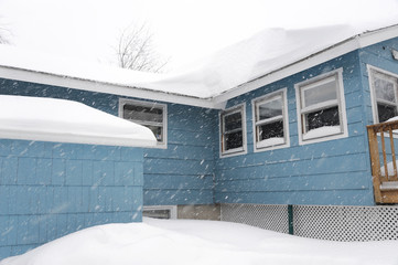 house after blizzard with thick snow on roof and surround