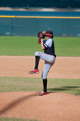 Little league baseball pitcher in wind up throwing the ball.