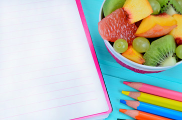 empty notebook with salad fruit on table