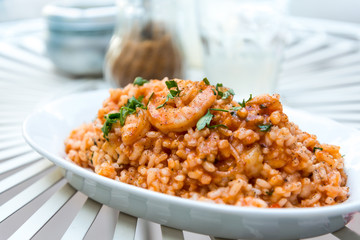 Tasty risotto with Shrimp, fresh herbs vegetables on a white pla