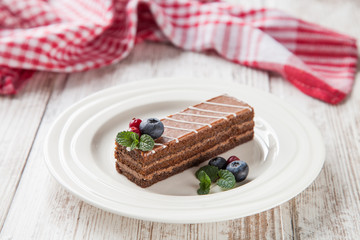 piece of chocolate cake with berries in a plate on a table, selective focus