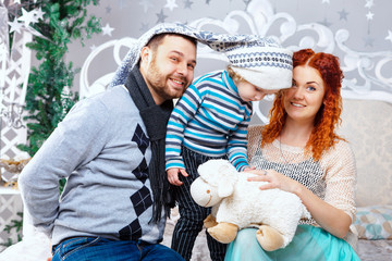 Christmas happy family of three persons and fir tree with gift boxes over white bedroom background