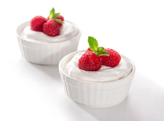 bowl of whipped cream with raspberries and  mint leaves  close-up on white background
