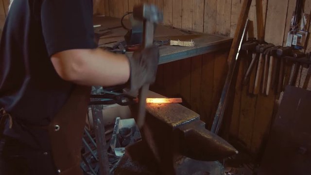 Woman blacksmith forges a horseshoe.