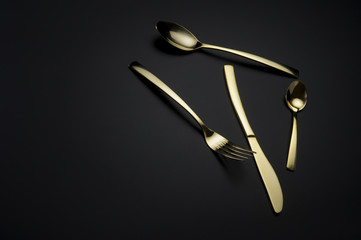 Two spoons, knife and fork on dark background