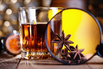 Glass of whiskey, magnifying glass, anise and cinnamone