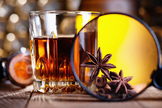 Glass of whiskey, magnifying glass, anise and cinnamone