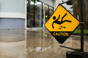 "man icon slip on wet floor", yellow and black rectangle signage for customer to walk carefully on wet floor at mall opened air area after rain