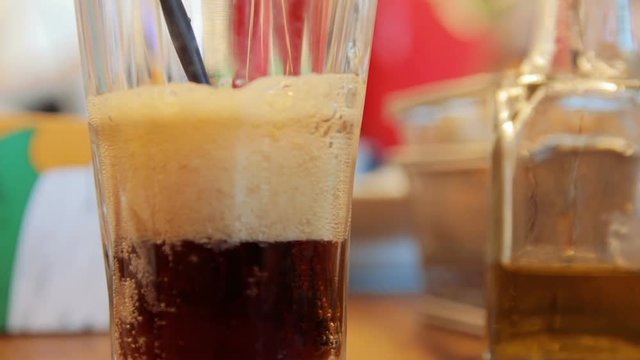 Pouring cola into a glass with ice on a table. Closeup selective focus.
