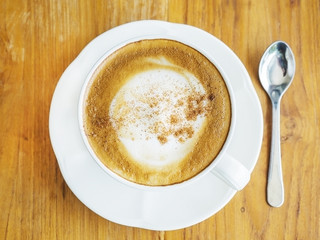 Top view of coffee cup with spoon over wooden table, light from right side window