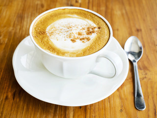 Coffee cup with spoon over wooden table, light from right side window
