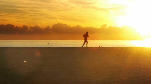 Healthy man running along beach at dawn