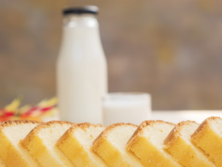 Butter cake and bottle with glass of milk on white wooden table