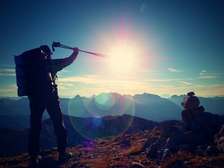 Lens flare defect. Happy alone adult backpacker with raised poles