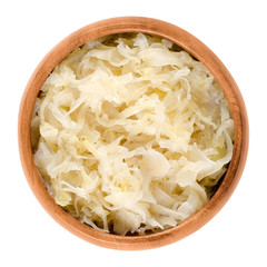 German sauerkraut in wooden bowl over white. Finely cut cabbage, fermented by lactic acid bacteria...
