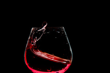 Fototapeta na wymiar Splash of wine in the glass on dark backround