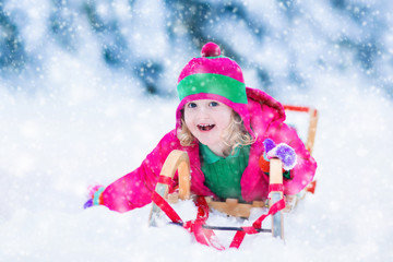 Fototapeta na wymiar Little girl enjoying a sleigh ride in winter
