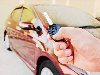 Man's hand is holding remote key pointing to his car