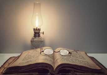 Opened vintage book (Psalter) with old eyeglasses and kerosene lantern