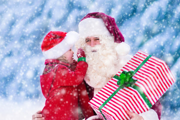 Santa Claus talking to little girl in snowy park