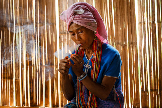 Female karen hill tribe is smoking tobacco pipe traditional in the cottage of northern Thailand at Mae Klang Luang, Mae Chaem, Chiang Mai Province
