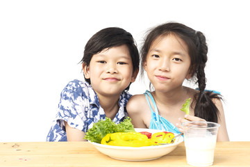 Asian lovely boy showing enjoy expression with fresh colorful vegetables and glass of milk isolated over white background