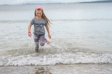 Happy little kid girl having fun with running through water in o