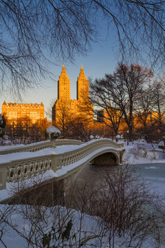 Fototapeta Zimowy wschód słońca Central Parku na zamarzniętym jeziorze z budynkami Bow Bridge i Upper West Side. Manhattan, Nowy Jork