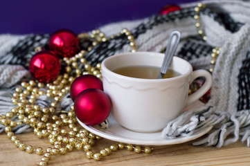 Green tea in white small cup and red christmas balls and golden chain for home decoration. Christmas morning concept