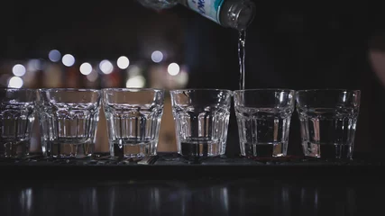 Foto auf Acrylglas Der Barkeeper schenkt Wodka in Gläser ein © Tkachenko Alexey
