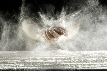 hands and splash of flour with black background 