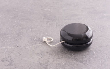 Black wooden yoyo on stone table with copy space. Close up of vintage toy. Concept of nostalgia, childhood and old-fashioned entertainment.