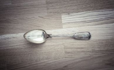 Silver spoon lying on wooden table. Still life of vintage cutlery in kitchen. Concept of eating, cooking or restaurant.