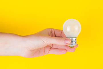 bulb in the hand on a yellow background