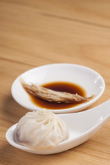 Xiao Long Bao in spoon and dipping sauce on wood  table