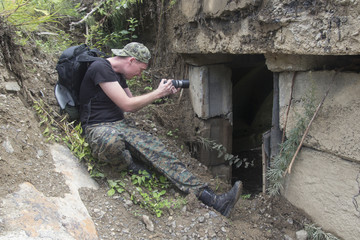 Military press photographer takes a report sitting at a collapsed building